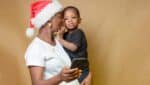 An African woman holding a smart phone with a Christmas cap on h